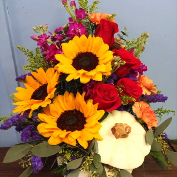 Mixed bouquet with sunflowers, red roses, and a white pumpkin container