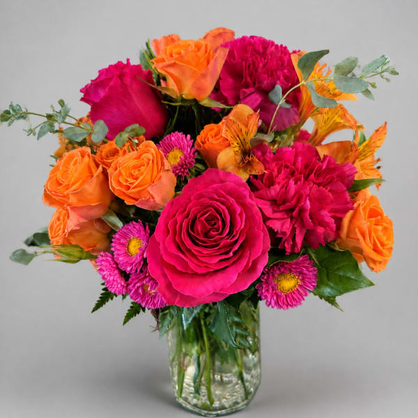 Bright pink and orange bouquet in a clear glass vase