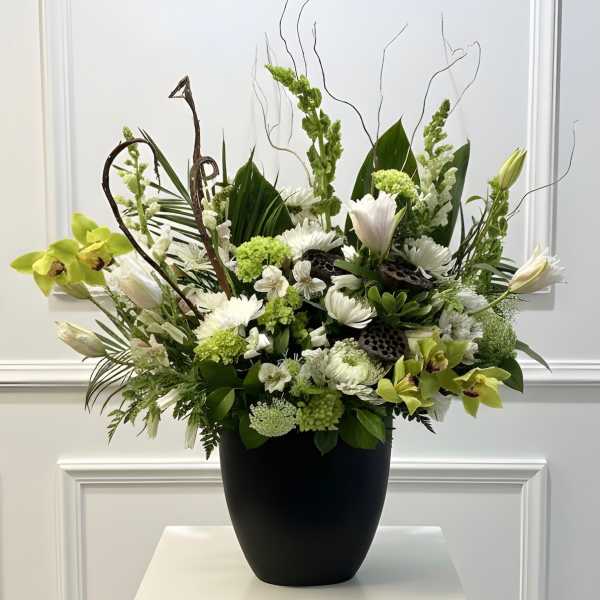 White and green floral arrangement in a black vase