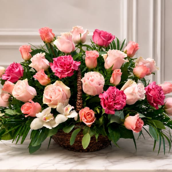 Pink and peach roses arranged in a woven basket with white orchids