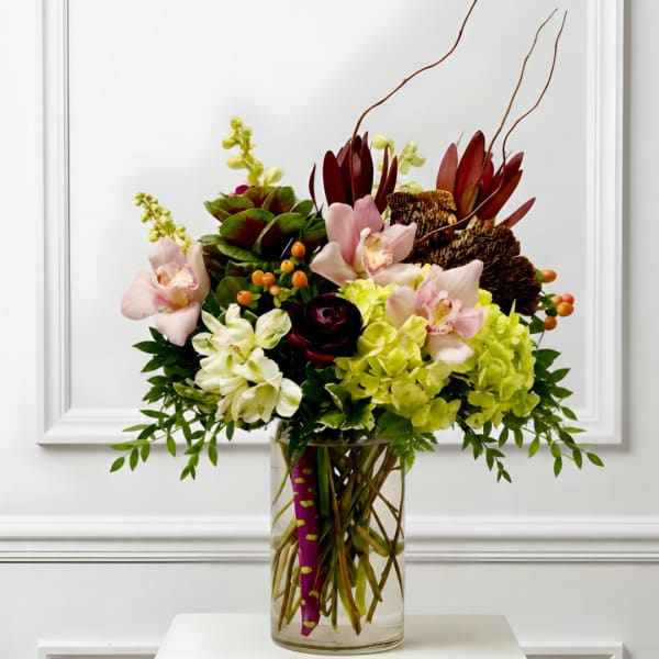 Mixed floral arrangement in a clear glass vase with pink, white, and burgundy blooms