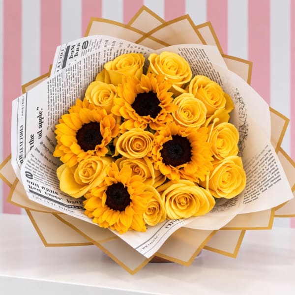 Yellow roses and sunflowers wrapped in newspaper-style paper