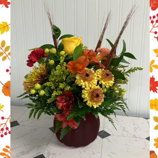 Mixed floral arrangement in a burgundy vase with yellow, orange, and red blooms