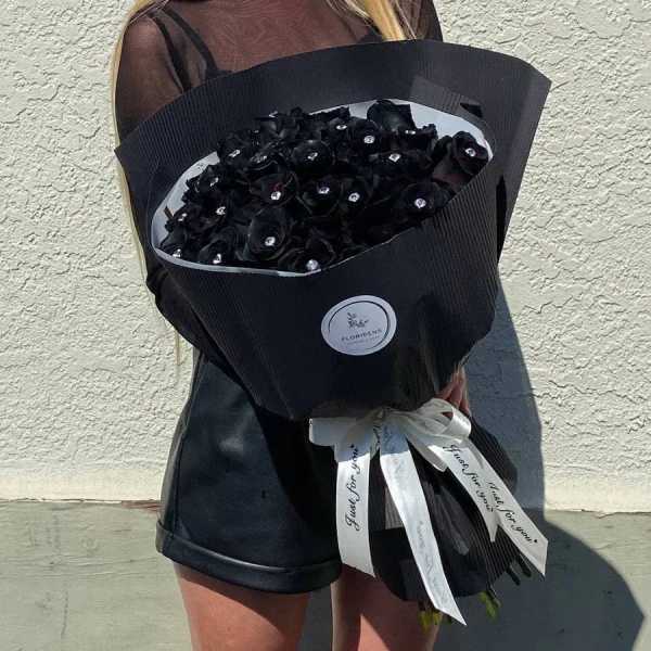 Large bouquet of black roses wrapped in black paper with a white ribbon