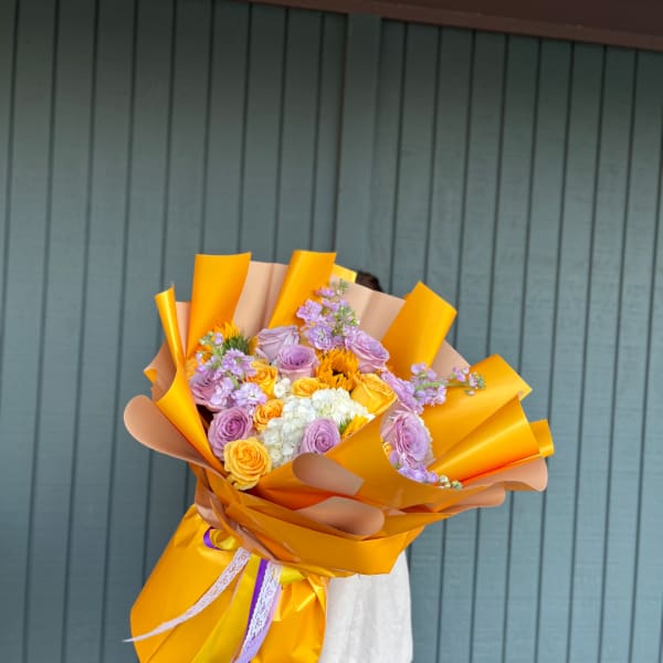 Bouquet of lavender and yellow roses wrapped in bright orange paper