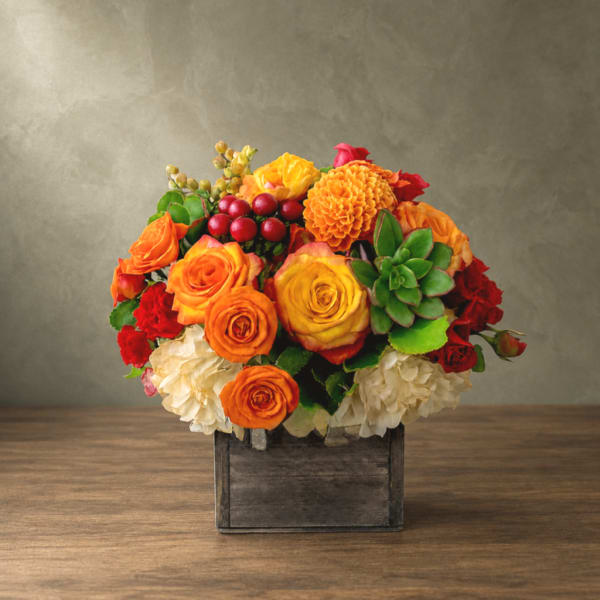Mixed orange and red flower arrangement in a wooden box
