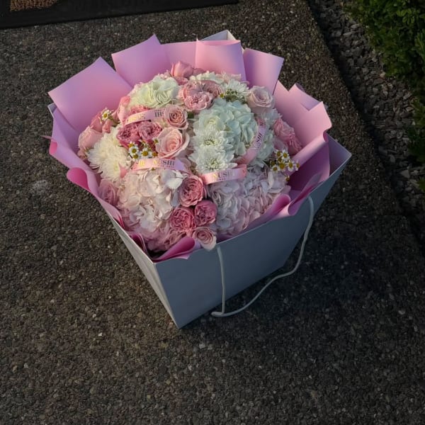 Pink and white bouquet in pastel wrapping with roses and hydrangeas
