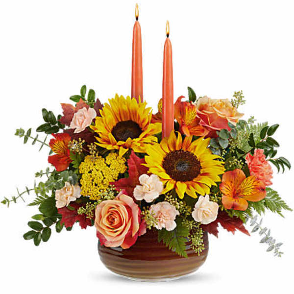 Sunflower and rose arrangement with two orange taper candles in a low bowl