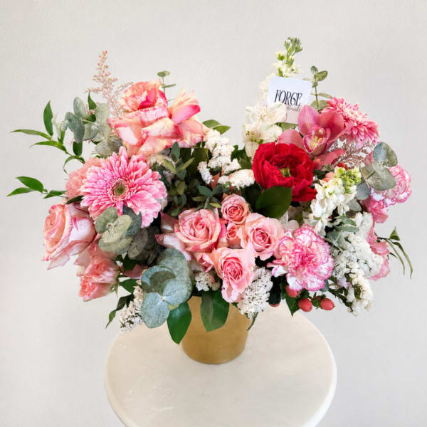 Pink and white mixed flower arrangement in a gold vase