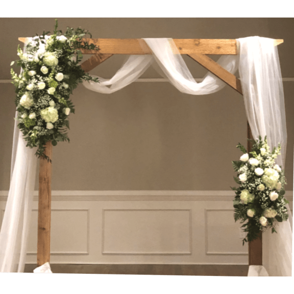 White floral arrangements on a wooden wedding arch with sheer draping