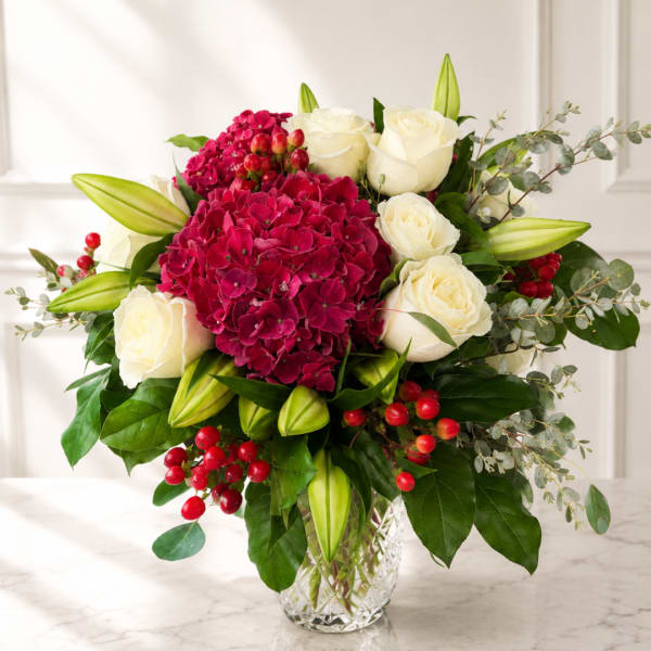 Bouquet of white roses and magenta hydrangeas in a clear glass vase