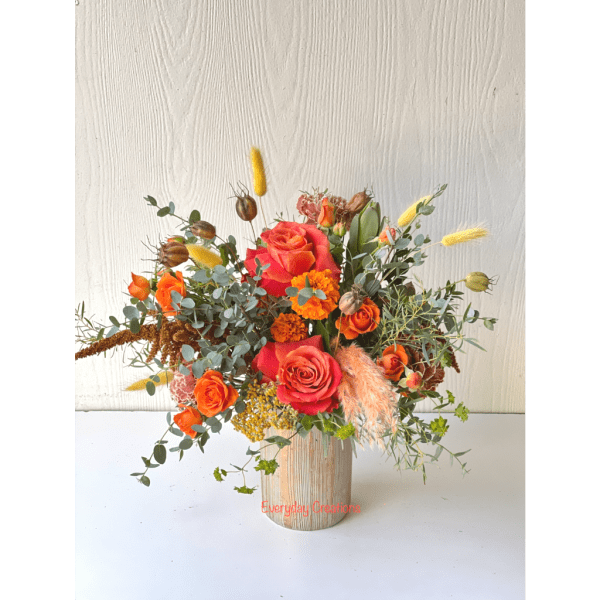 Orange and pink rose arrangement in a wooden vase