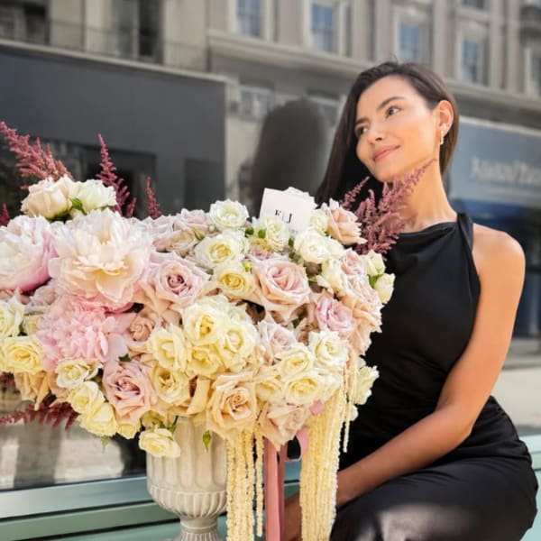 Large pastel rose arrangement in a white pedestal vase