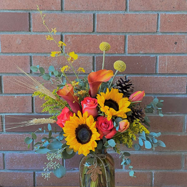 Mixed bouquet in a glass jar with sunflowers, calla lilies, and roses