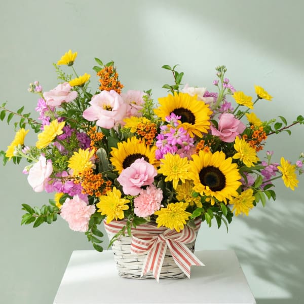 Mixed bouquet in a white basket with a striped ribbon