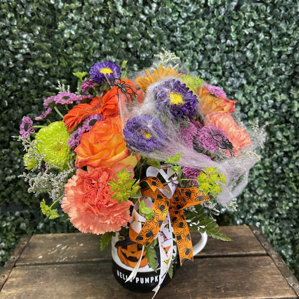 Halloween bouquet in a pumpkin mug with orange, purple, and pink flowers