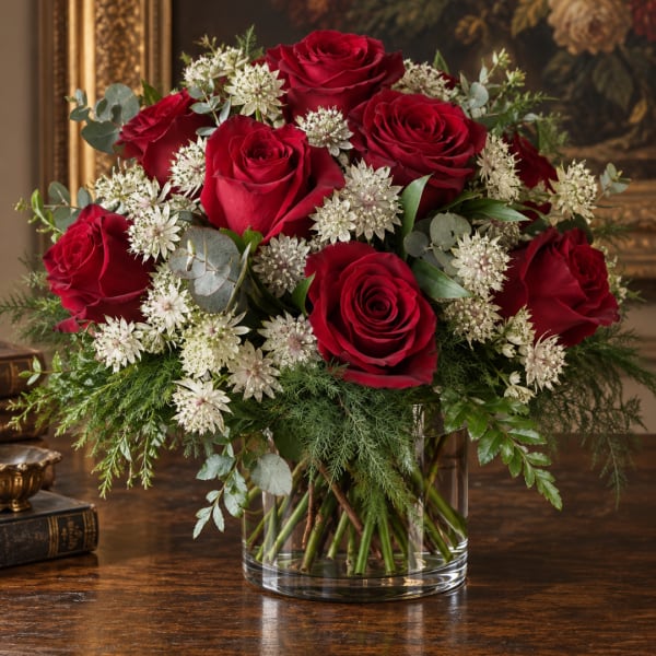 Red roses and white star-shaped flowers in a clear glass vase