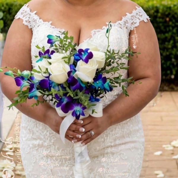 Bride holding a bouquet of white roses and purple-blue orchids