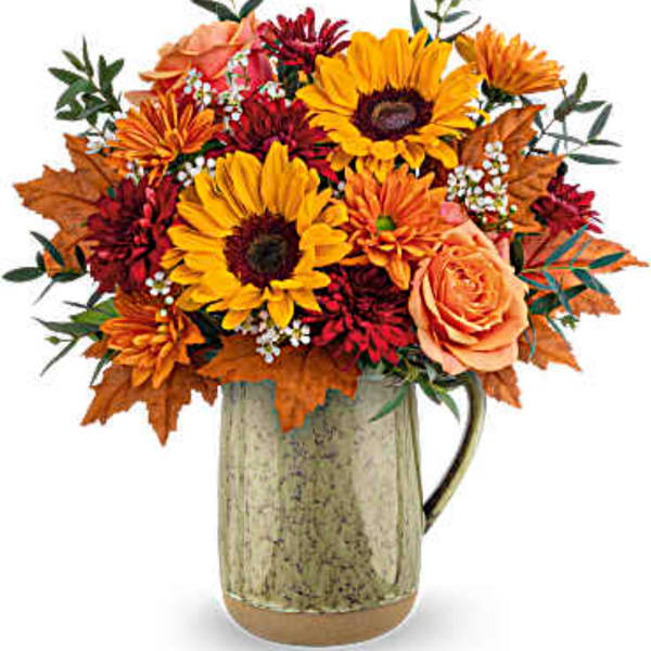 Autumn bouquet of sunflowers, roses, and mums in a metal pitcher