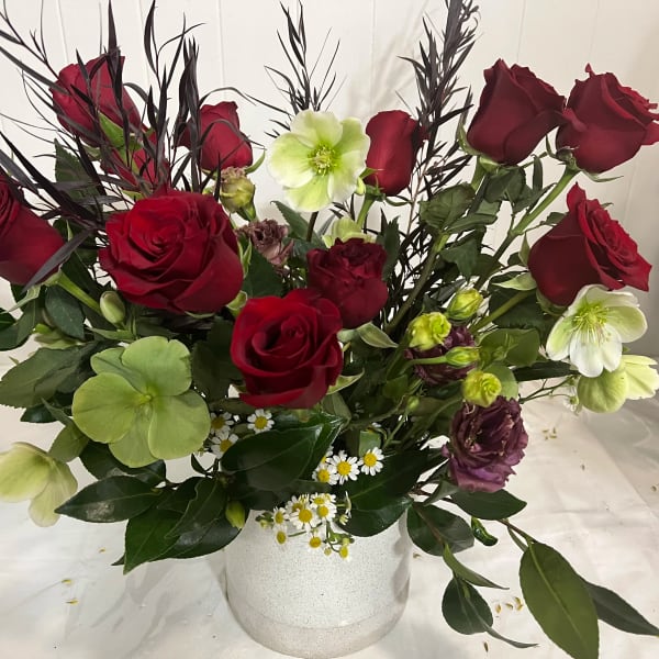Red roses and pale green flowers arranged in a white vase