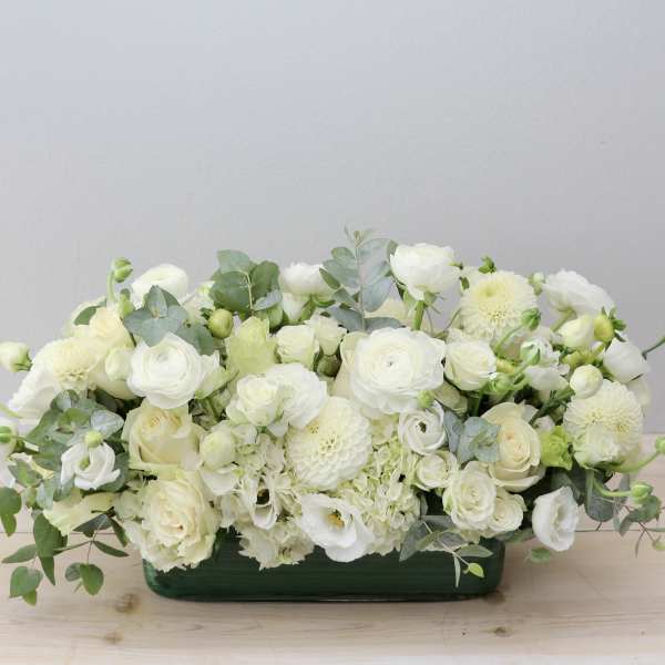 White floral arrangement in a low green container