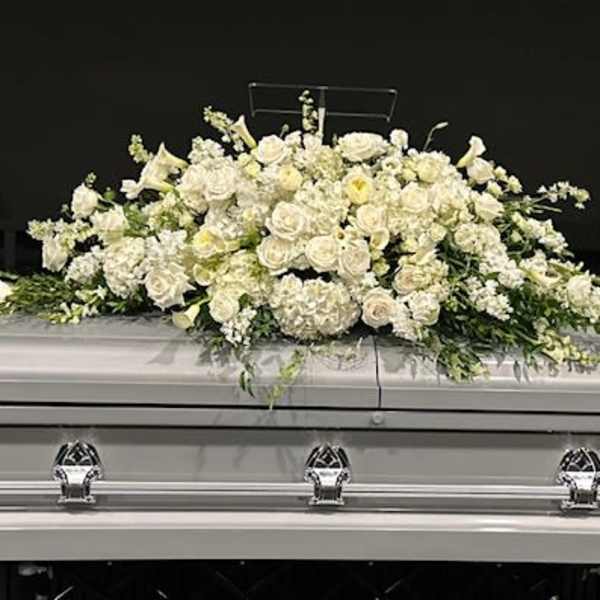 White floral casket spray on a silver casket
