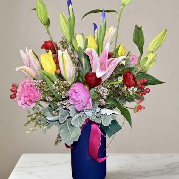 Colorful bouquet of lilies, tulips, and carnations in a blue vase
