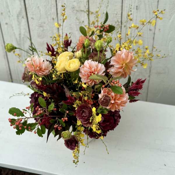 Mixed bouquet with peach, yellow, and burgundy flowers in a vase