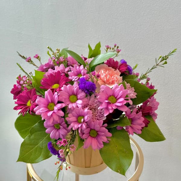 Pink daisy bouquet in a small wooden container