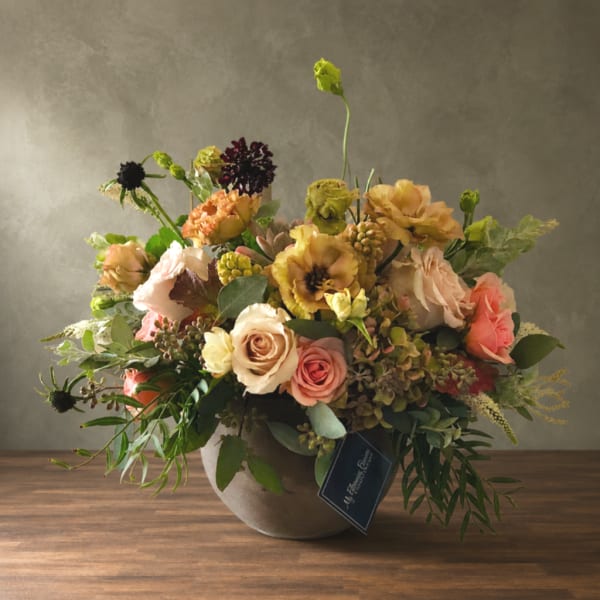Mixed floral arrangement in a round vase with roses and peach blooms