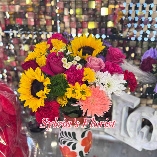 Mixed bouquet with sunflowers, roses, and daisies in a painted vase