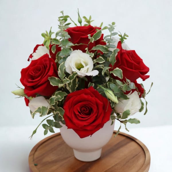 Red and white roses arranged in a white vase