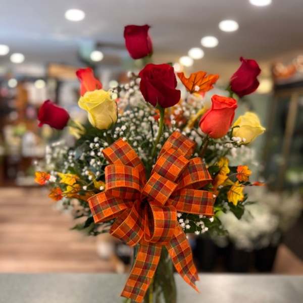 Bouquet of red and yellow roses in a glass vase with an orange plaid bow