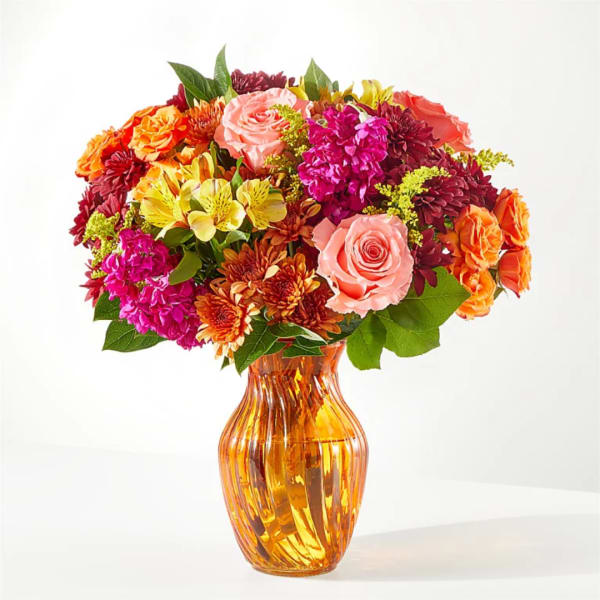 Mixed bouquet of roses, chrysanthemums, and alstroemeria in an amber glass vase