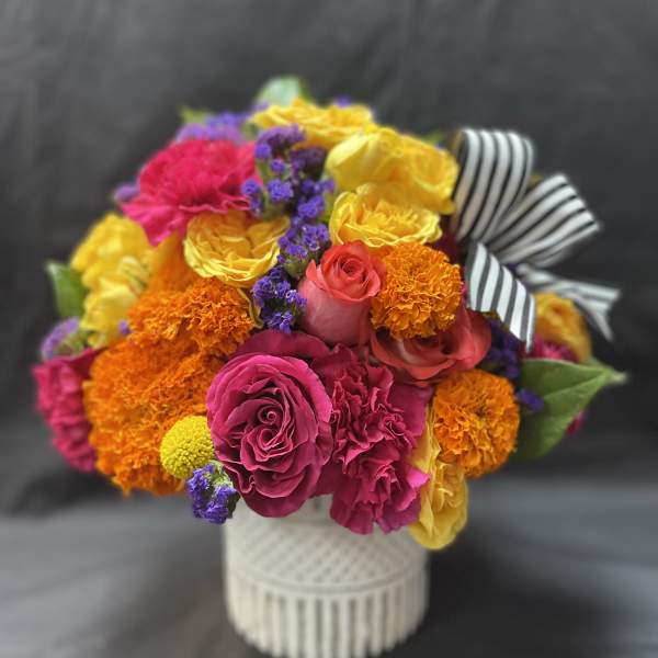 Bright mixed bouquet in a white vase with a striped ribbon