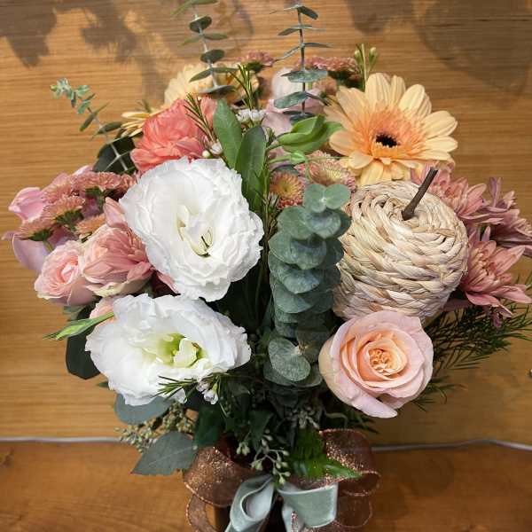 Pink and white mixed flower arrangement in a black vase with ribbon