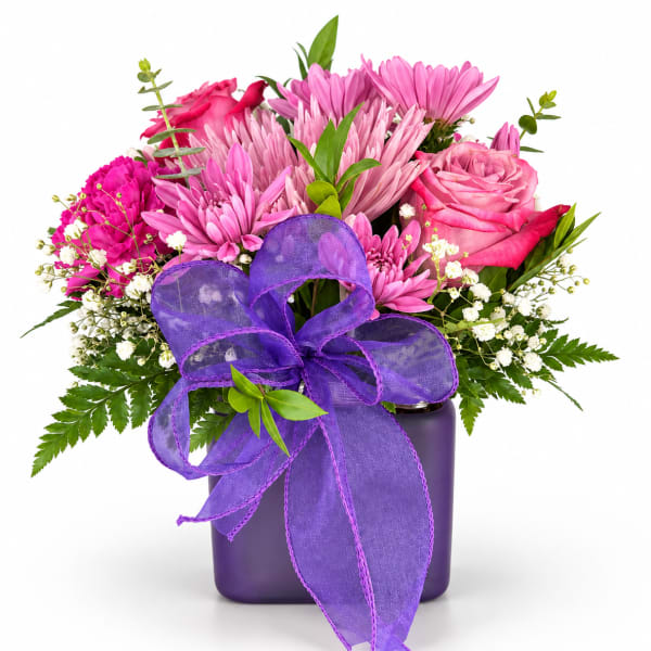 Pink and purple flower arrangement in a dark vase with a large purple ribbon