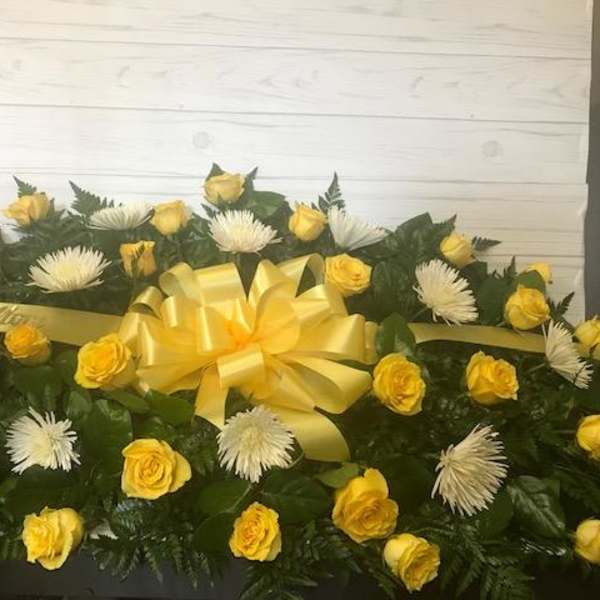 Yellow roses and white spider mums arranged with a yellow ribbon bow