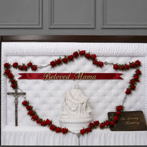 Red rose funeral casket spray with memorial ribbon and crucifix