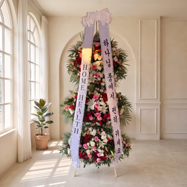 Tall standing floral wreath with pink, white, and red flowers and ribbon banners