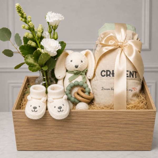 Gift basket with white flowers, a plush bunny, baby booties, and a wrapped item