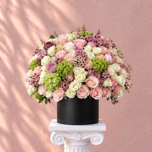 Round bouquet of pink, white, and lavender roses in a black box