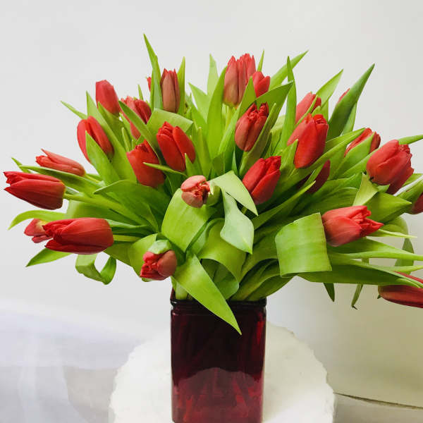 Red tulips arranged in a dark glass vase