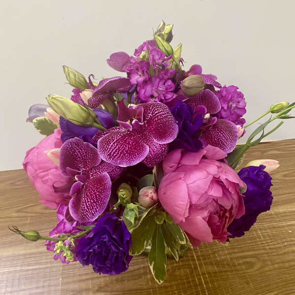 Pink and purple bouquet with orchids and peonies on a table