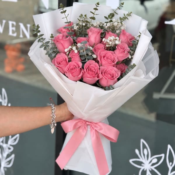 Pink roses wrapped in white paper with a pink ribbon