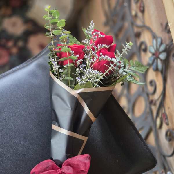 Bouquet of red roses wrapped in black paper with a pink bow