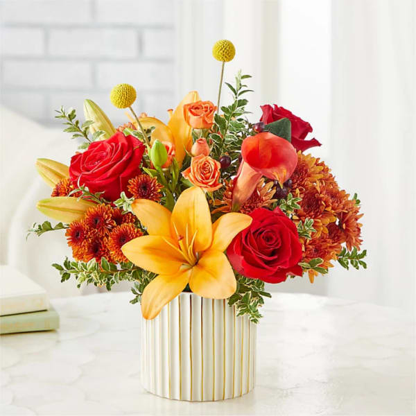 Bright mixed bouquet with roses, lilies, and mums in a striped vase