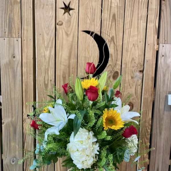 Bouquet of red roses, white lilies, and yellow sunflowers in a glass vase