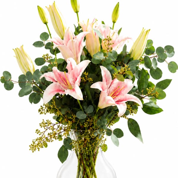 Pink lilies in a clear glass vase with eucalyptus greenery