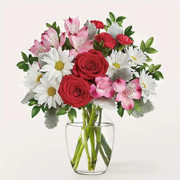 Bouquet of red roses, white daisies, and pink alstroemeria in a glass vase